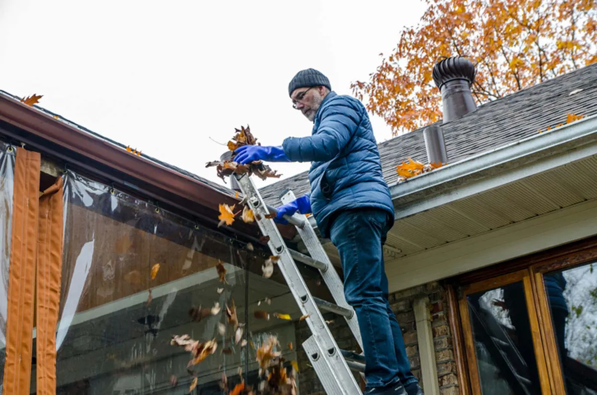 Homeowner clearing debris from a yard drain grate before rain season